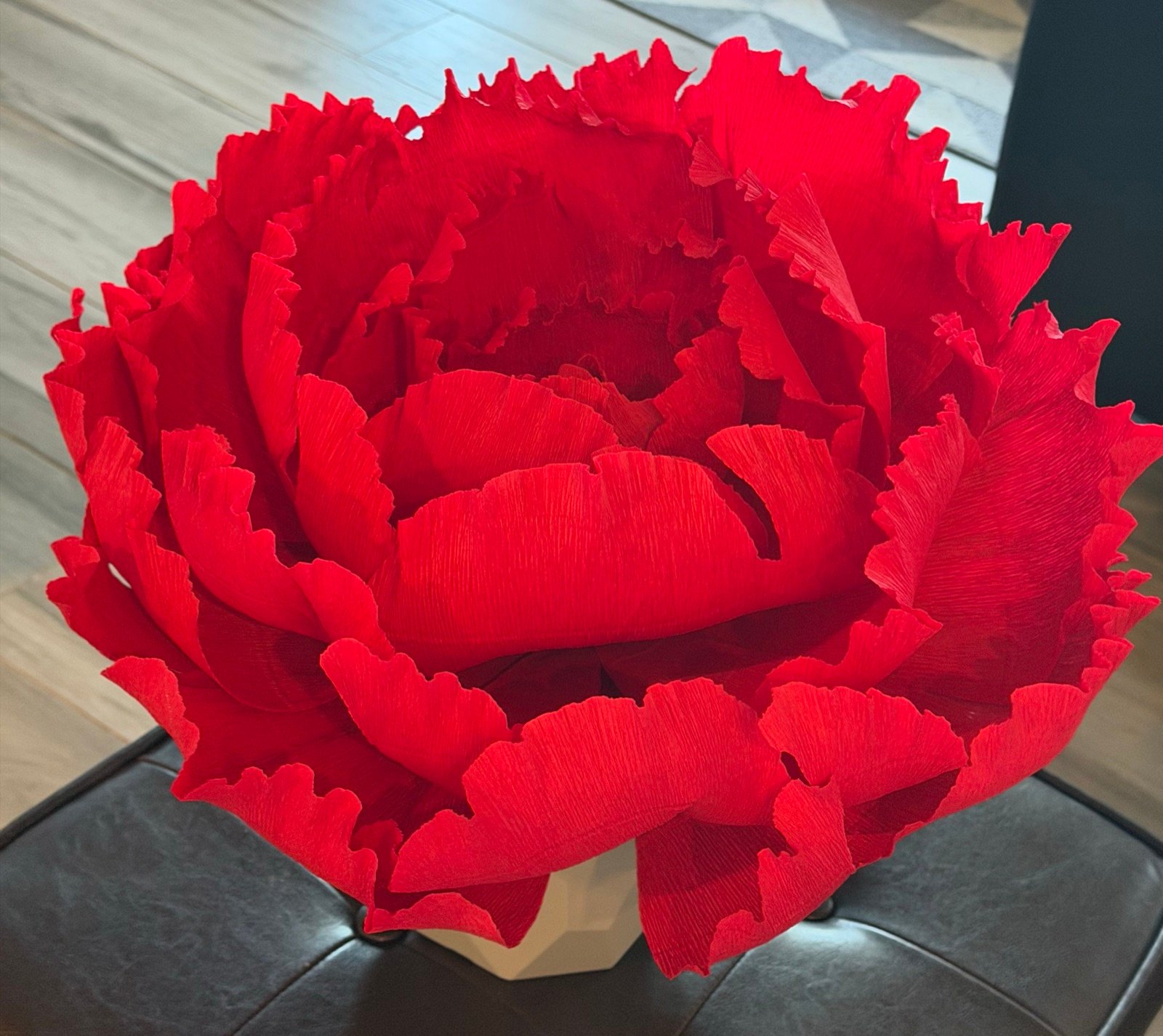 A giant red ruffled paper peony in a white pot